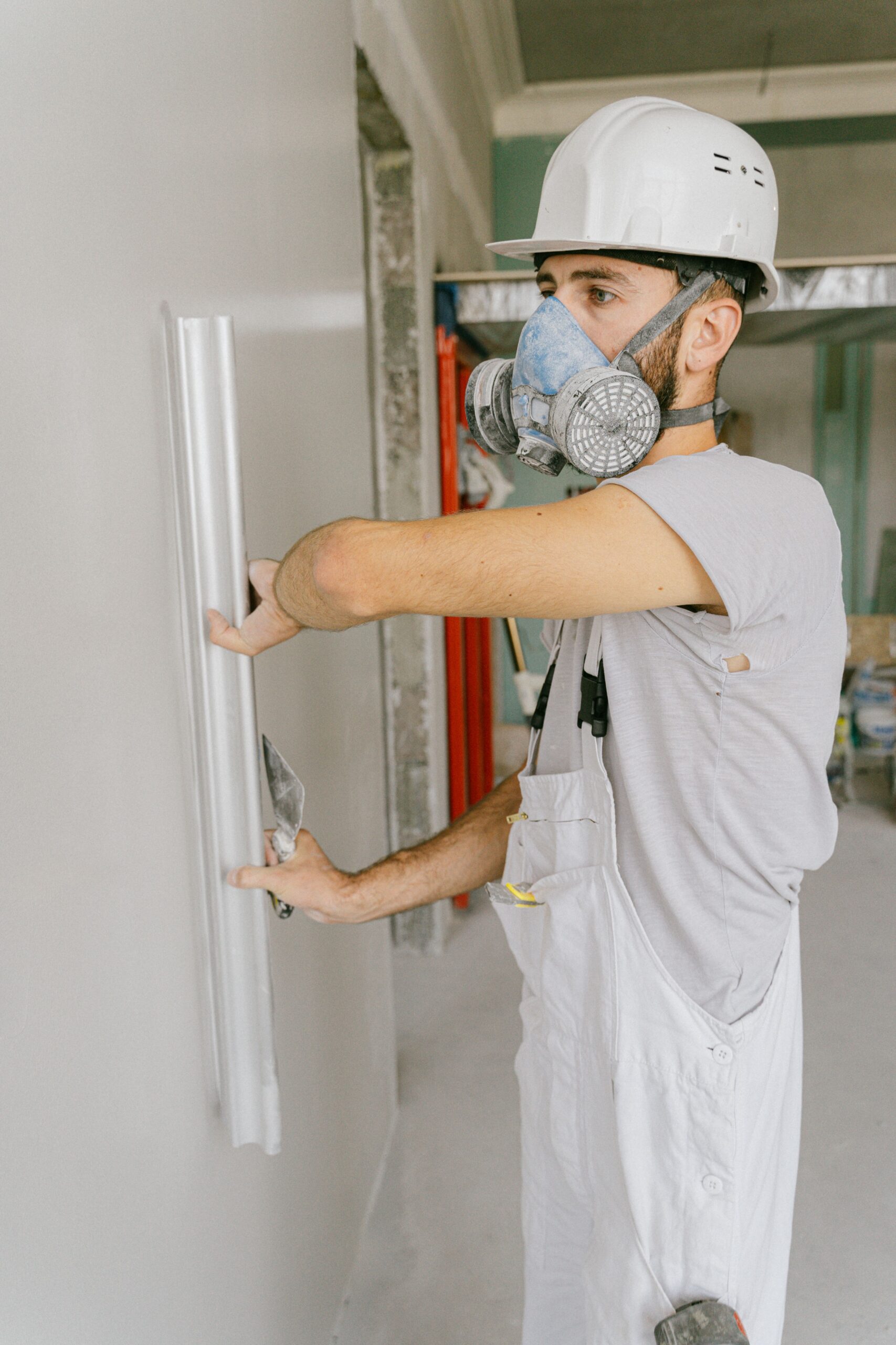 Construction worker smoothing a freshly repaired wall with a trowel, demonstrating the Execute step of a thorough repair process