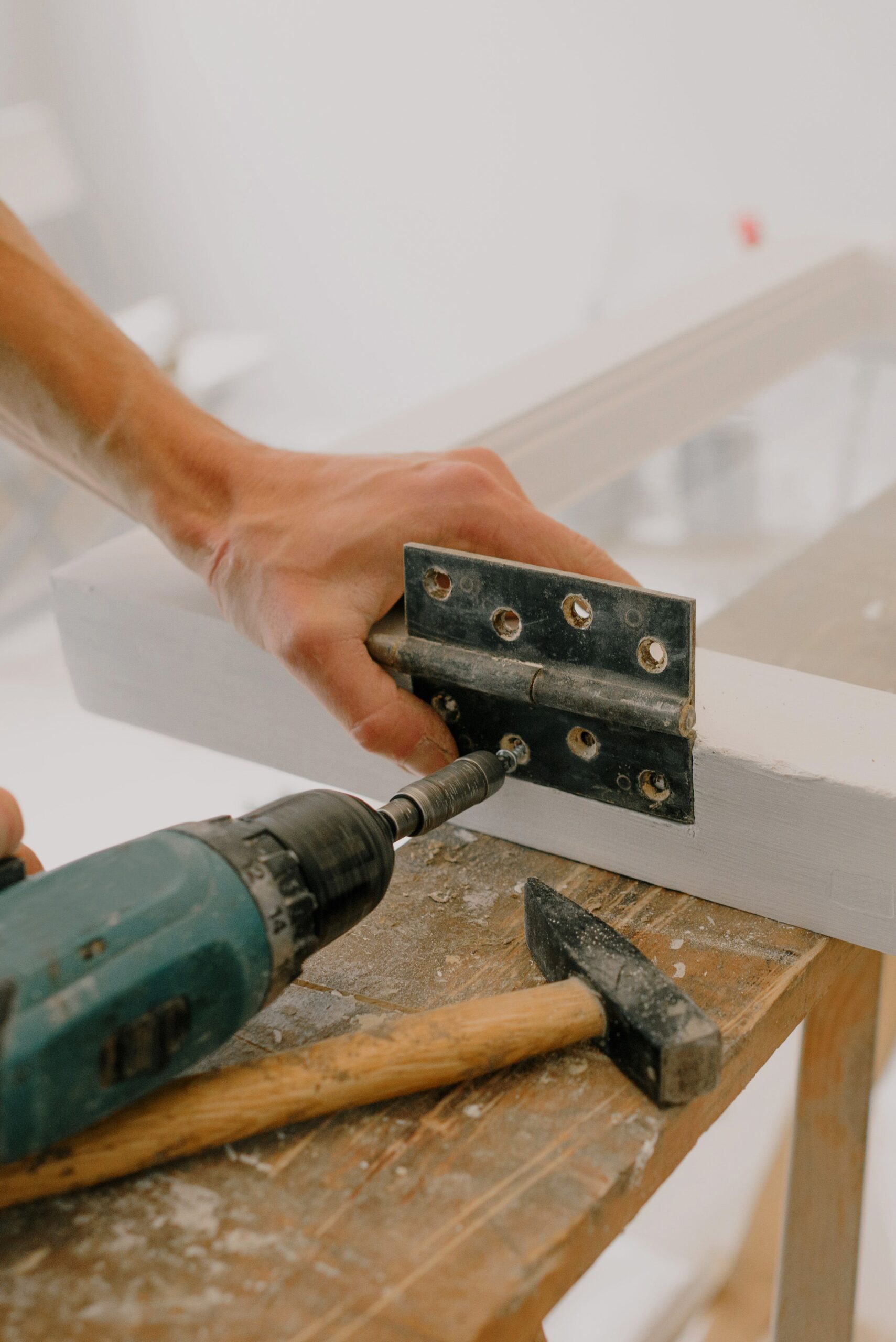 Professional handyman using a drill to install a hinge on a window frame, representing reliable small-job repair work