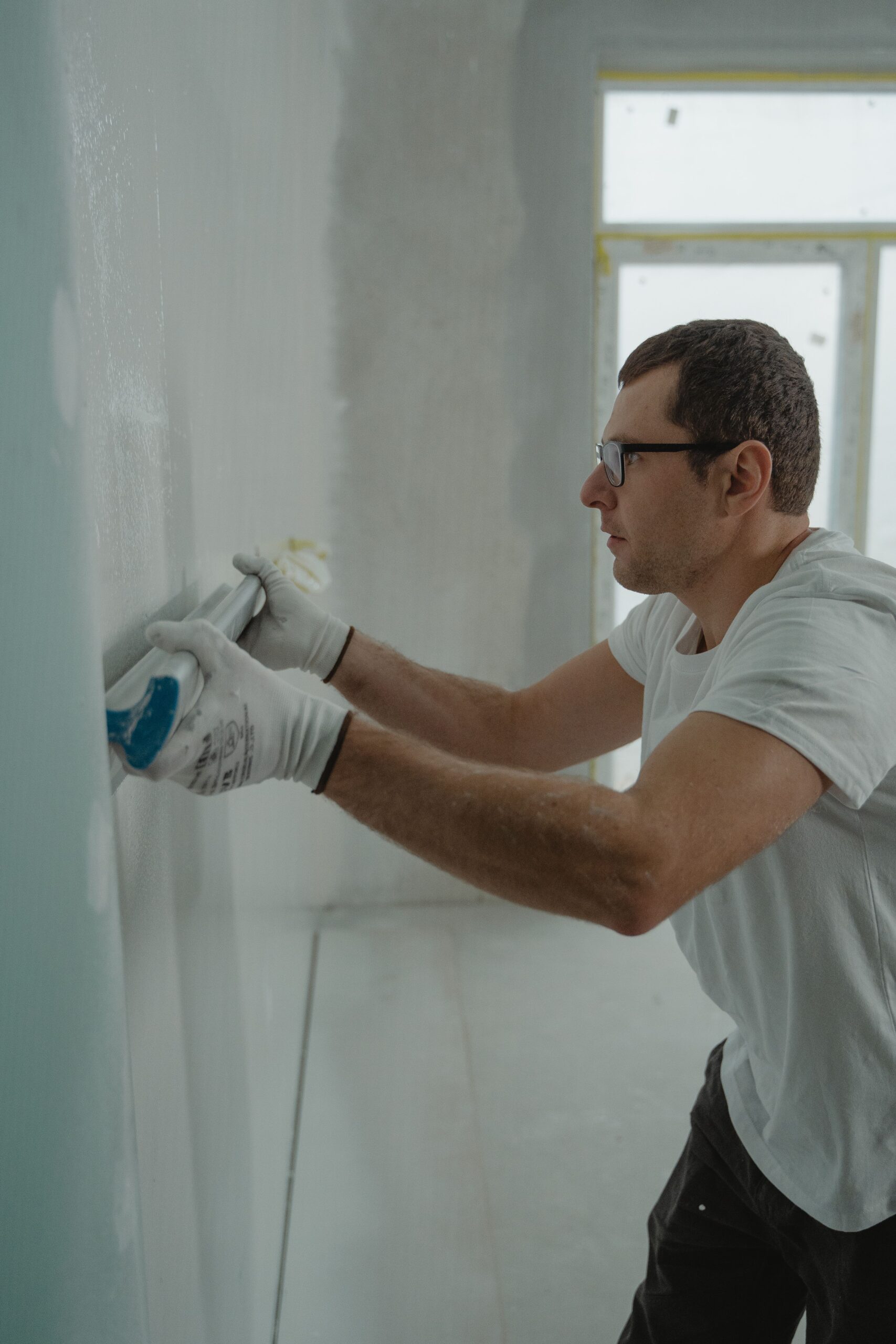Handyman carefully applying drywall compound during a diagnostic-first repair, illustrating the FIXRR Method's Inspect and Execute steps